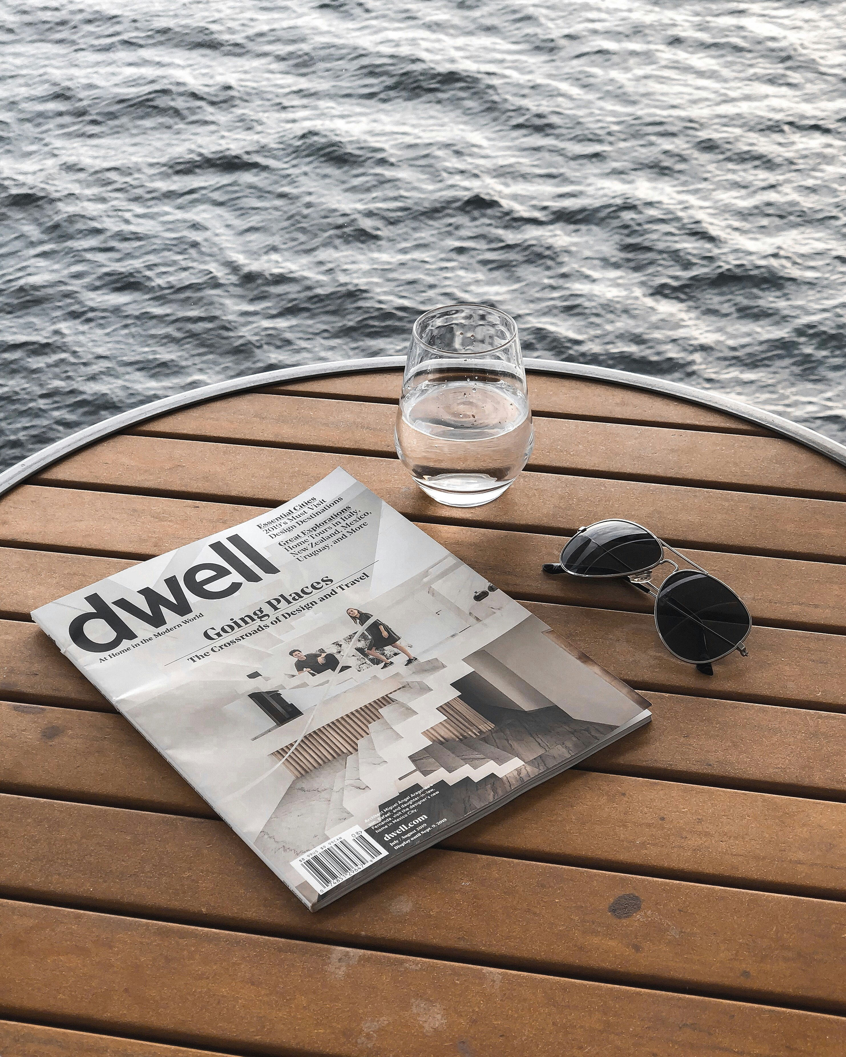 cup of water beside magazine and sunglasses